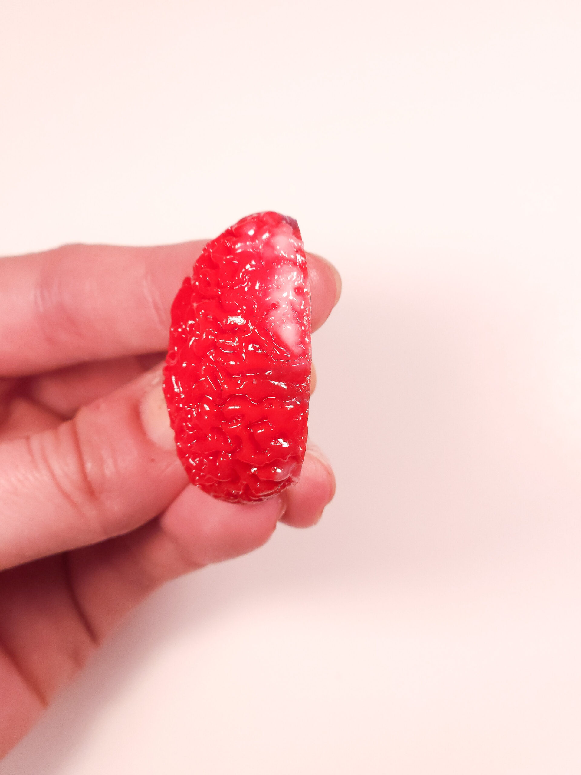 Top view of a glossy red brain magnet showing a white swipe on the medial top edge.