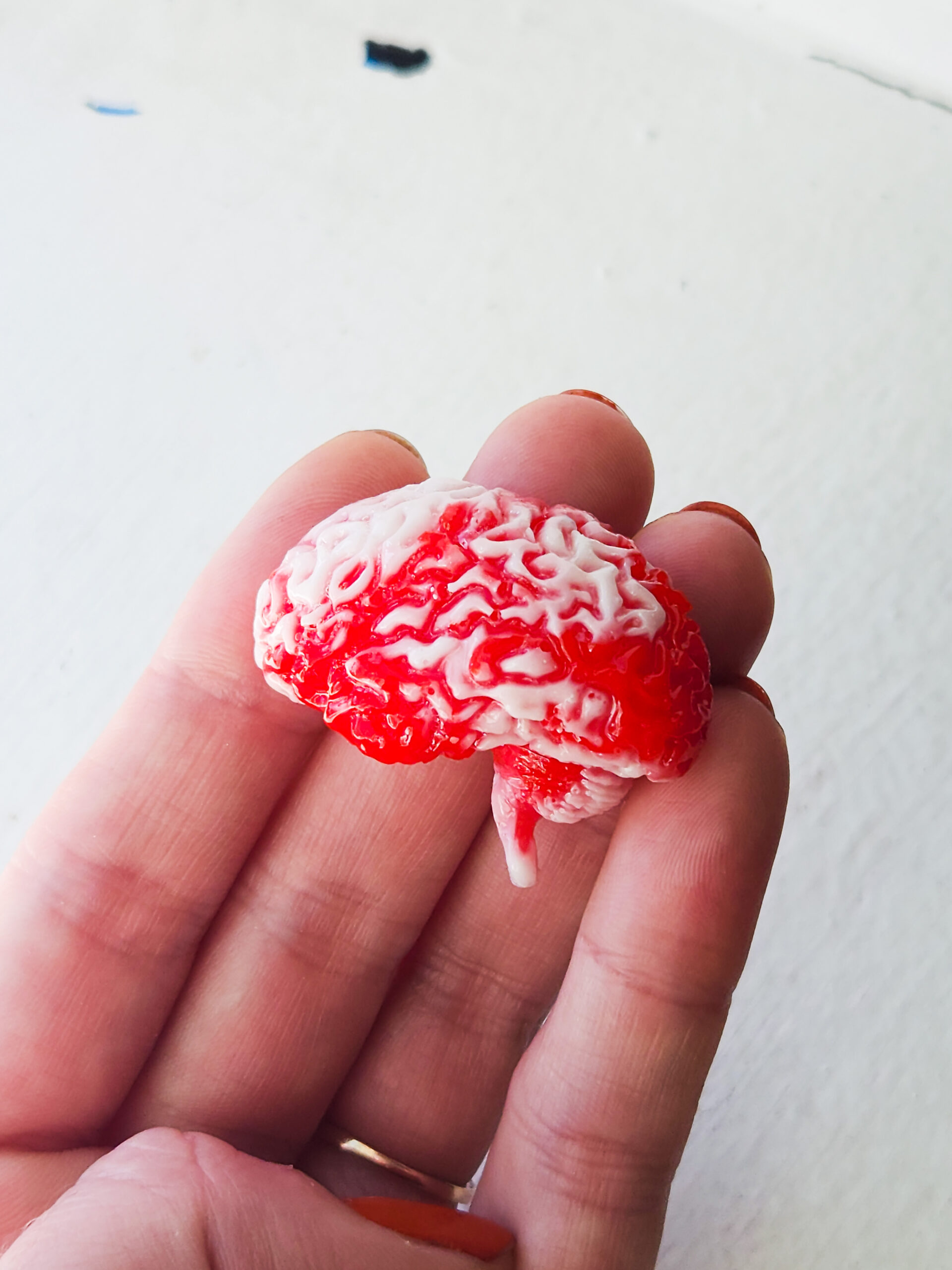 3D resin magnet shaped like a human brain, colored with red and white opaque swirls.