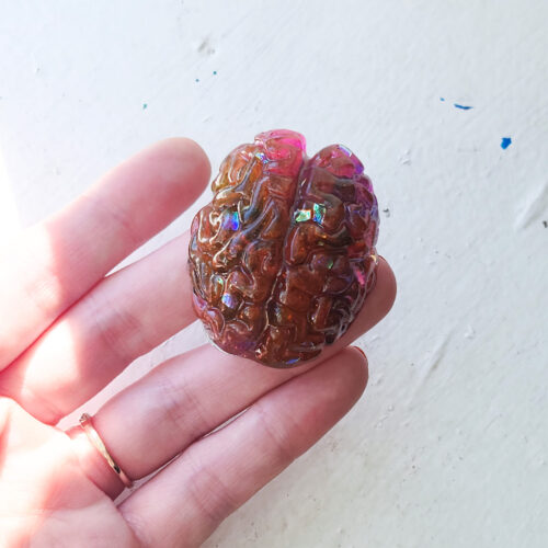 Glossy 3D pink-orange brain magnet with holographic flecks inside.