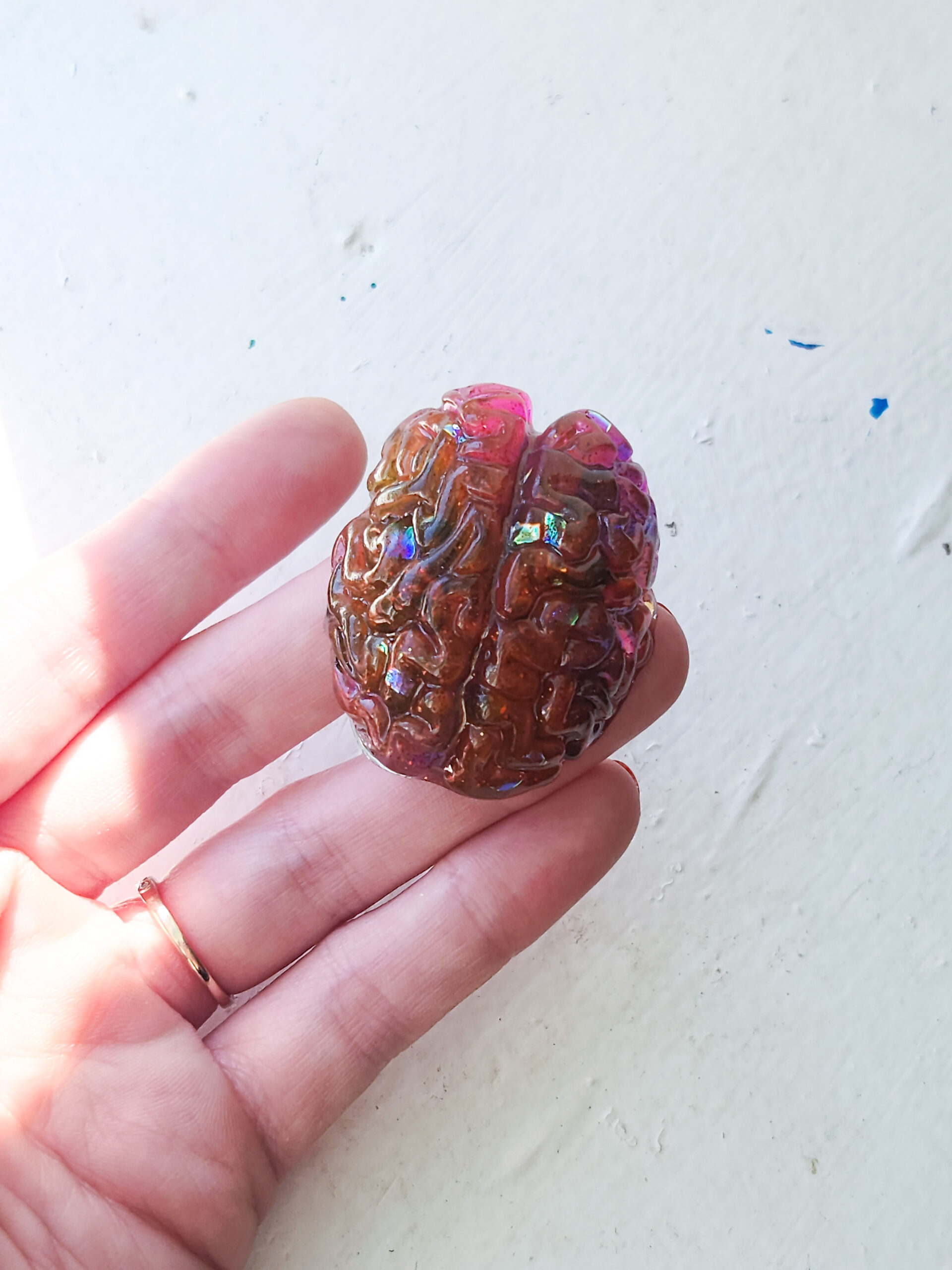 Glossy 3D pink-orange brain magnet with holographic flecks inside.